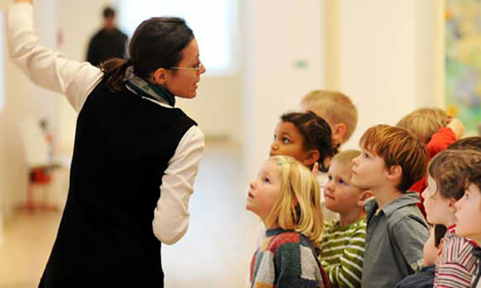 Kinder hören der Ausstellungsführerin zu
