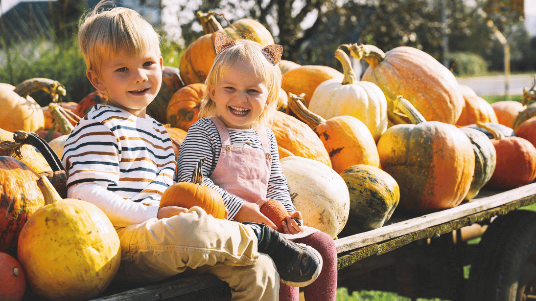 Kinder die bei einem fest mit Kürbissen zusammen sitzen