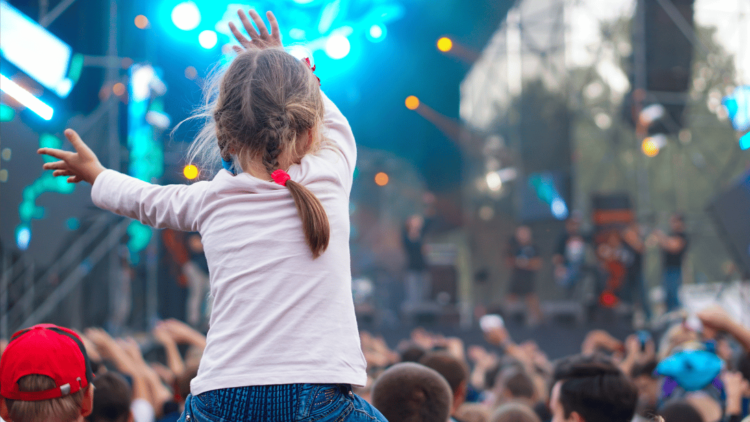 Kind das auf den Schultern des Vaters einem Konzert lauscht 
