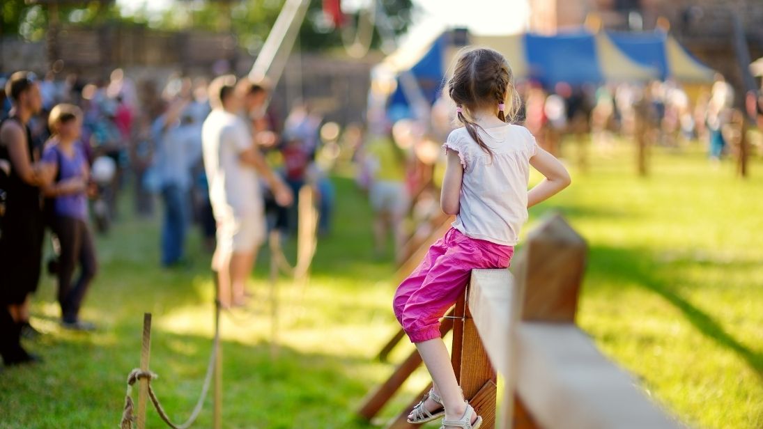 Mädchen sitzt bei Fest auf einem Zaun